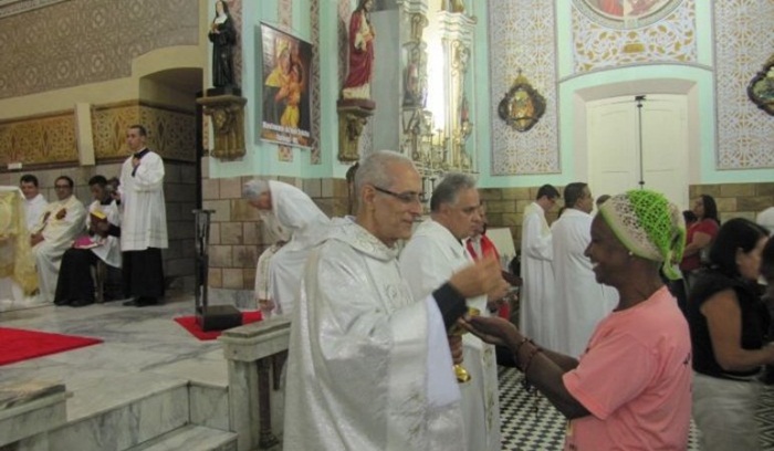Padre Fernando entregando a sagrada eucaristia a uma fiel. 